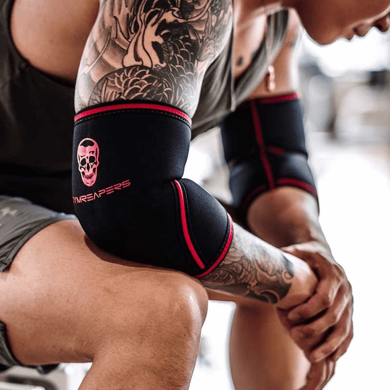 Alt Text : Coudière de sport noir/rouge, ajustable et résistante pour un soutien et un confort supérieurs lors de l'entraînement.
